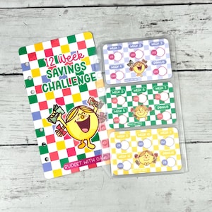 Può includere: Un tracker per il risparmio di 12 settimane con un motivo a scacchi colorato e un personaggio dei cartoni animati che tiene in mano del denaro. Il tracker include una custodia in plastica trasparente con tre inserti etichettati dalla settimana 1 alla 12, con cerchi.