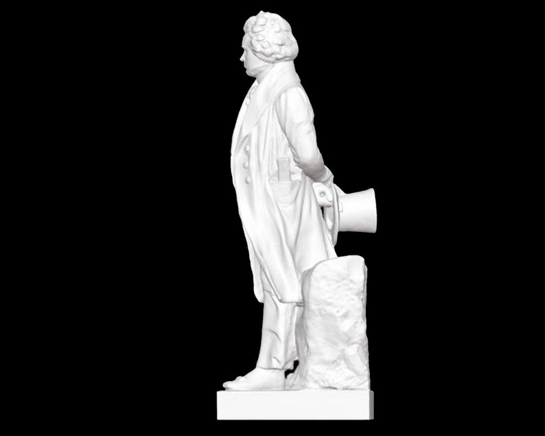 May include: A white marble statue of a man in a long coat, standing with his right hand on a rock and holding a hat in his left hand.