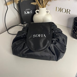May include: Black drawstring makeup bag with a white embroidered name "SOFIA" on the front.