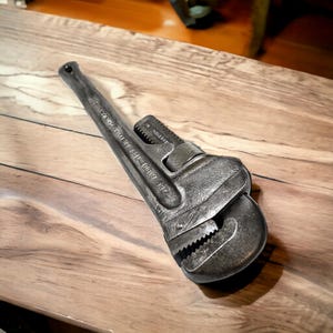 Puede incluir: Una llave de tubo vintage de color plateado con el texto "THE RIDGE TOOL CO.  ELYRIA, OHIO" en el mango.