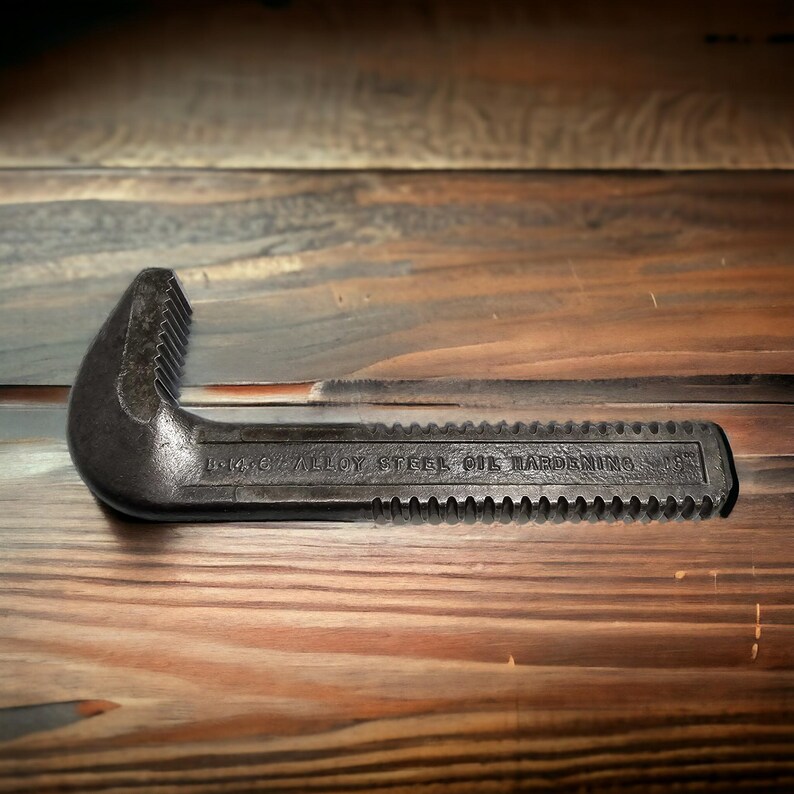 Puede incluir: Una llave de tubo negra con el texto "14-6" Alloy Steel Oil Hardening 157" en el lateral.