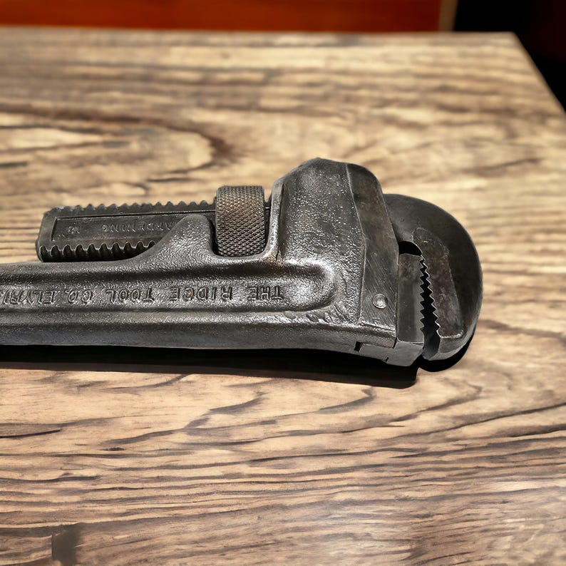 Puede incluir: Una llave de tubo negra con el texto "THE RIDGE TOOL CO. ELMIRA, N.Y." en el mango.