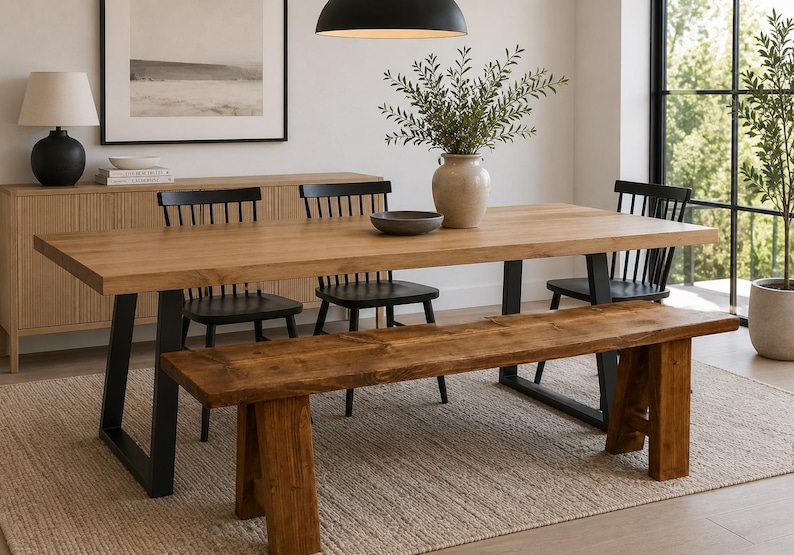 May include: A light wood dining table with black metal legs, surrounded by black chairs and a wooden bench. A beige rug and a vase with greenery complete the dining room setting. The table is approximately 244 cm long.