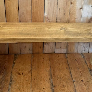 May include: A rustic wooden bench with a natural finish. The bench has a simple design with a rectangular top and two A-frame legs.