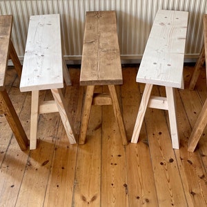 May include: Five wooden benches with a rustic finish. The benches are made of natural wood and have a simple design. They are arranged in a row on a wooden floor.