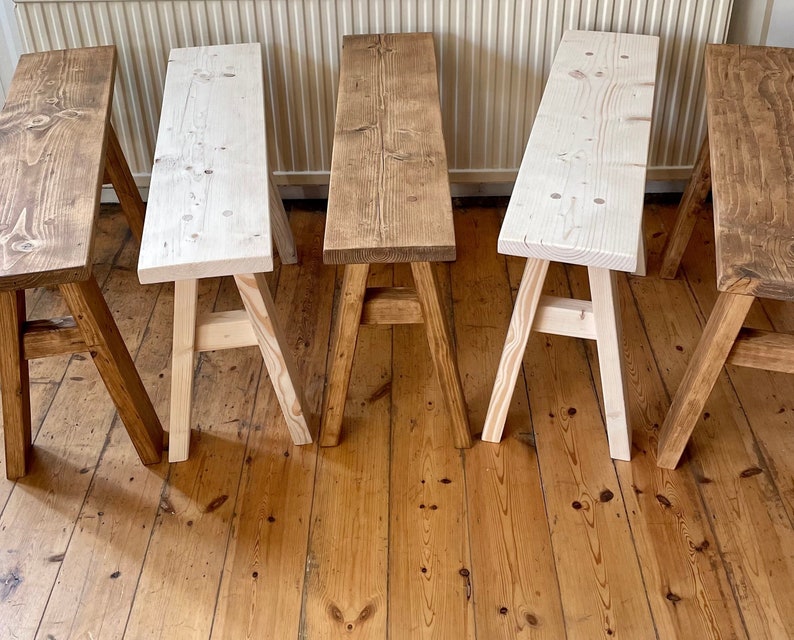 May include: Five wooden benches with a rustic finish. The benches are made of natural wood and have a simple design. They are arranged in a row on a wooden floor.