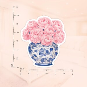 May include: A bouquet of pink peonies in a blue and white porcelain vase with a floral pattern. The vase is on a white background.
