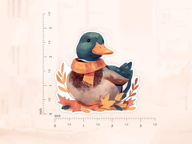 May include: A sticker featuring a watercolor illustration of a duck wearing an orange scarf, surrounded by autumn leaves. The duck has a teal head and a bright orange beak. The sticker measures approximately 3 inches in length.