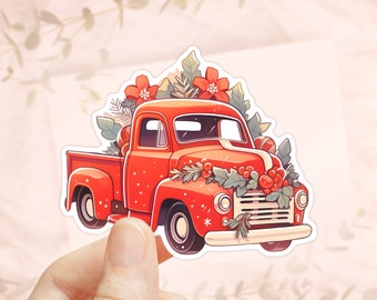 Könnte beinhalten: Ein roter Vintage-Pickup-Truck, geschmückt mit einem Weihnachtskranz, Stechpalmen und Weihnachtssternen. Der Truck transportiert ein verpacktes Geschenk und ist bereit, festliche Freude zu verbreiten.