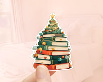 Puede incluir: Un árbol de Navidad hecho de libros apilados con adornos verdes, rojos y dorados. El árbol está decorado con una estrella amarilla en la parte superior.