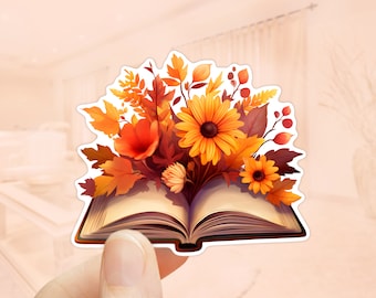 May include: An open book with a bouquet of autumn-coloured flowers bursting from its pages. The flowers are a mix of orange, yellow, and red, with leaves in shades of brown and orange.