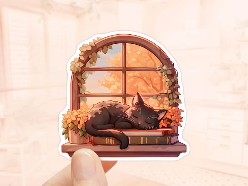 May include: A sticker featuring a black cat sleeping peacefully on a stack of books in front of a window. The window is framed by a wooden arch and adorned with green leaves. The background shows an autumn scene with orange and yellow foliage.