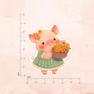 May include: A pink pig wearing a blue and white checkered dress holds a pot of colorful flowers.