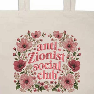 K&ouml;nnte beinhalten: Cremefarbene Tragetasche mit dem Text "anti Zionist social club" in Rosa, umgeben von einem floralen Kranz aus rosa und roten Blumen. Die Tasche hat zwei cremefarbene Griffe.