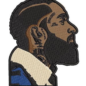 May include: Embroidered patch featuring a side profile of a man with a beard and a distinctive hairstyle. The patch uses black, tan, and blue thread. The design is detailed, with visible facial features and clothing details.