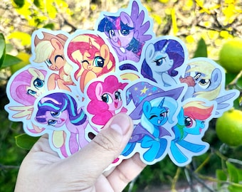 May include: A collection of die-cut vinyl stickers featuring various colorful cartoon ponies with large eyes, including characters in shades of pink, purple, blue, and yellow, with one pony wearing a blue wizard hat with yellow stars.
