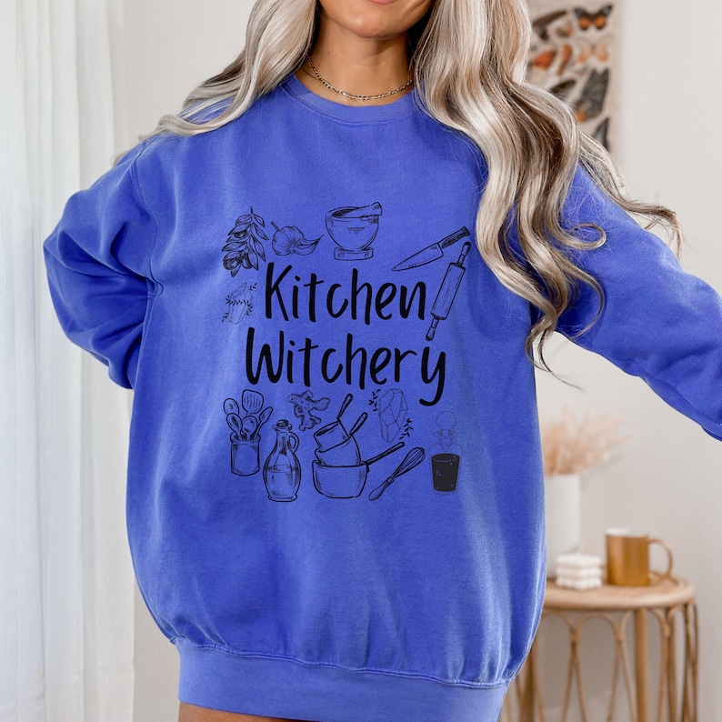Może przedstawiać: Szarfa w kolorze kr&oacute;lewskiego błękitu z nadrukiem graficznym przedstawiającym kuchenne narzędzia i tekstem "Kitchen Witchery".