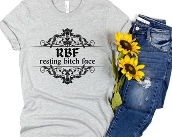 May include: A gray t-shirt with a black graphic design that says "RBF resting bitch face" in a decorative font.