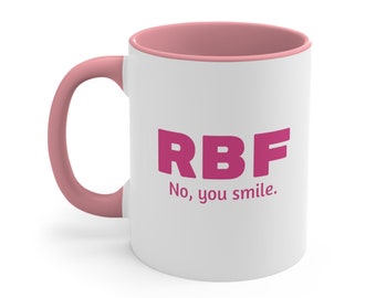 Może przedstawiać: Biały kubek ceramiczny z różowym rantem i uchwytem. Kubek ma różowy napis "RBF No, you smile."