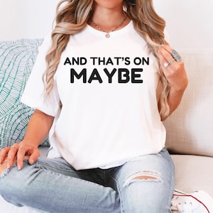 Może przedstawiać: Biała koszulka z czarnym napisem "And that's on maybe".