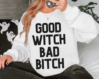 Może przedstawiać: Biała bluza z czarnym napisem "Good Witch Bad Bitch".