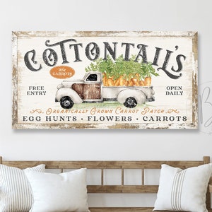 May include: A vintage-style sign with the text "COTTONTAILS" in large, bold letters. The sign features a cartoon illustration of a white pickup truck with a wooden bed filled with carrots. The text "FREE ENTRY" and "OPEN DAILY" is on the left and right sides of the sign. The sign also includes the text "ORGANICALLY GROWN CARROT PATCH, EGG HUNTS, FLOWERS, CARROTS".