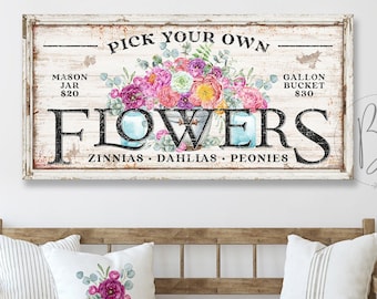 May include: A rustic wooden sign with the text "Pick Your Own Flowers" in black lettering. The sign features a watercolor illustration of a bouquet of pink, purple, and yellow flowers. The sign also includes the prices for mason jars and gallon buckets of flowers.