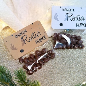 Puede incluir: Dos pequeñas bolsas de caramelos de chocolate con una etiqueta marrón y blanca que dice "Magische Rentier Pupse".
