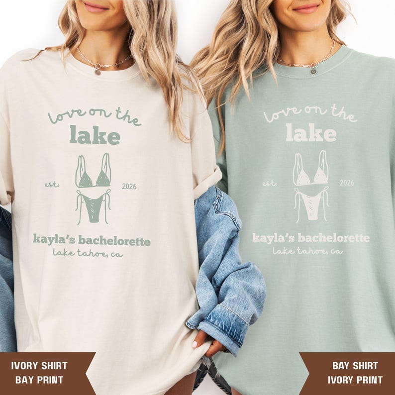 May include: Two long-sleeved shirts, one ivory and one bay, featuring the text "Love on the Lake" above a bikini graphic. The shirts also display "kayla's bachelorette" and "Lake Tahoe, CA". The ivory shirt has a bay print, and the bay shirt has an ivory print.