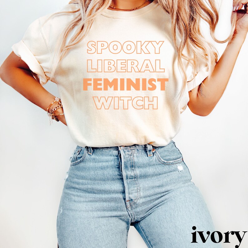 May include: A white t-shirt with the text "Spooky Liberal Feminist Witch" printed in orange.