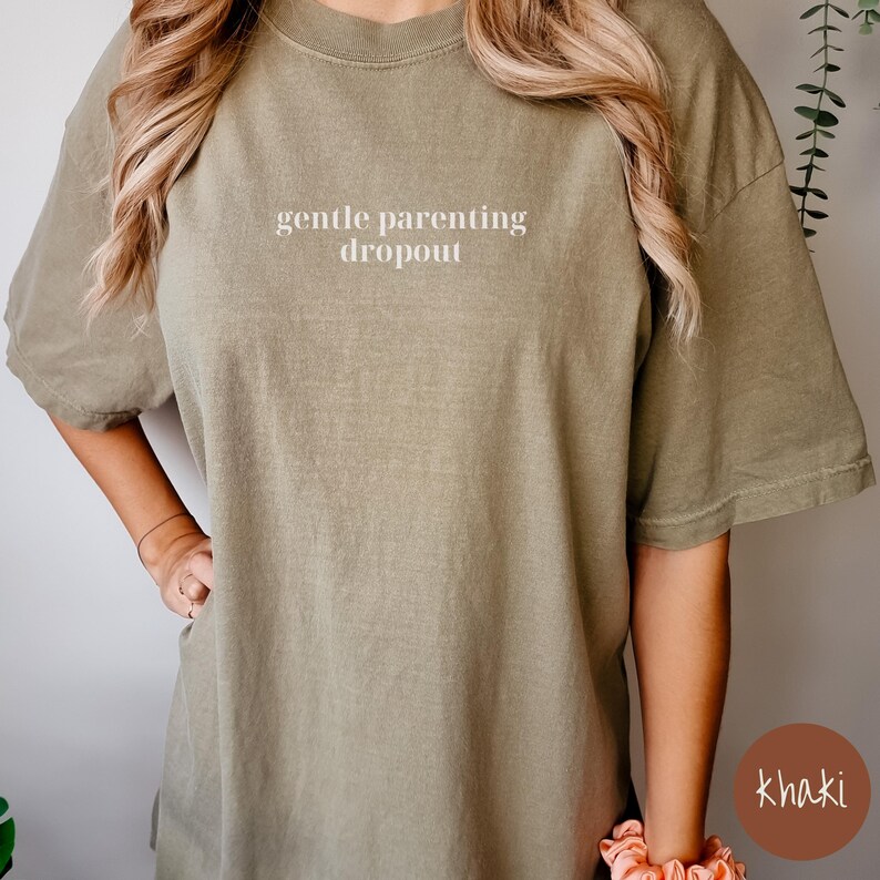 Op de afbeelding: Een kaki-kleurig T-shirt met de tekst "gentle parenting dropout" in wit gedrukt op de voorkant.