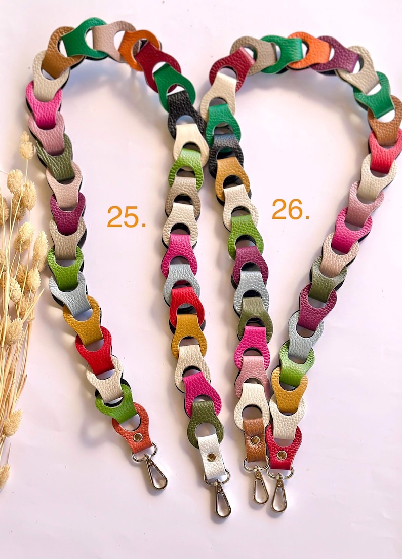 May include: Three colorful, linked leather purse straps. Each strap is made of multiple, interlocking leather pieces in various colors, including green, orange, pink, and white. The straps have silver-colored metal clasps at the ends for attachment.