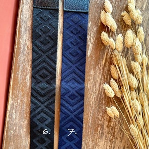 May include: Two fabric straps with gold clasps. The strap on the left is black with a geometric pattern. The strap on the right is navy blue with a geometric pattern. The straps are labeled "6." and "7."