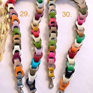 May include: Two colorful purse straps with a chain-link design. Each strap is made of leather in various colors, including pink, green, orange, and blue. The straps have silver-colored metal clasps at the ends for attaching to a purse or bag. The number 29 and 30 are printed on the image.