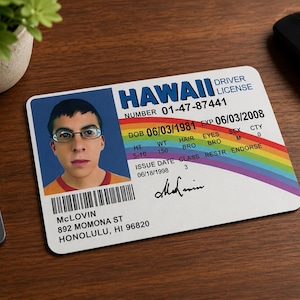 May include: A rectangular Hawaii driver licence card featuring a portrait of a person with glasses, a rainbow graphic, and the name McLovin. The card displays the number 01-47-87441, a date of birth of 06/03/1981, and an address of 892 Momona St, Honolulu, HI 96820.