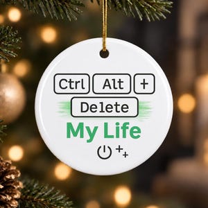 May include: A round white ceramic ornament featuring black keyboard key graphics labeled Ctrl, Alt, and Delete, with the green text My Life below. A power symbol and a plus sign are printed at the bottom, and a gold string is attached to the top.