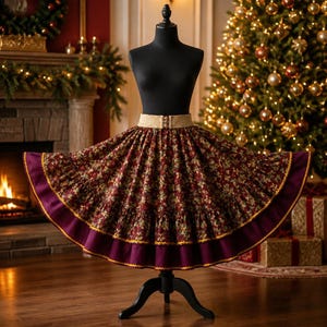 Puede incluir: Una falda larga de tela roja oscura con un patrón floral repetitivo, una cintura ancha de color beige y un dobladillo con volantes de color púrpura oscuro acentuado con un borde amarillo fino, sobre un torso de maniquí negro.