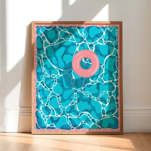 May include: A framed print of a blue and white abstract pattern depicting a swimming pool with a pink inflatable ring floating in the center.