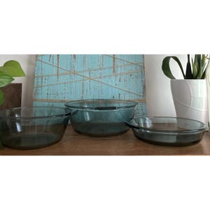 May include: Three glass baking dishes in various sizes. The dishes are a dark blue colour and have a slightly textured surface.
