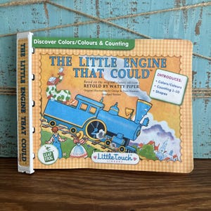 Könnte beinhalten: Kinderbuch "The Little Engine That Could" mit einer Illustration einer blauen Lokomotive. Das Cover zeigt "Entdecke Farben & Zählen" und führt Farben, Zählen 1-10 und Formen ein. Teil der Little Touch Library.