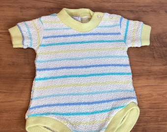 May include: A vintage baby romper with a textured, terrycloth-like fabric. The romper features horizontal stripes in light blue, turquoise, and yellow against a white background. The neckline and sleeve and leg openings are trimmed in yellow.