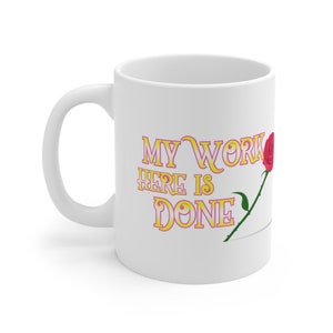 Könnte beinhalten: Weiße Keramiktasse mit einer rosa Rose und dem Text "My work here is done" in gelber und rosa Schrift.