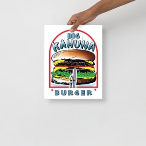 May include: A retro-style illustration of a large burger with the text "BIG KAHUNA BURGER" in a red, white, and blue arch. The burger is topped with lettuce, tomato, and a pickle. A surfer is standing on a surfboard in the middle of the burger.