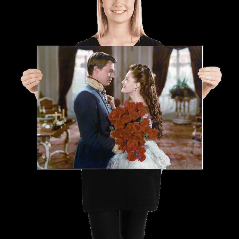 May include: A man in a military uniform holds a bouquet of red roses and looks at a woman in a white dress. The woman is smiling and looking at the man.