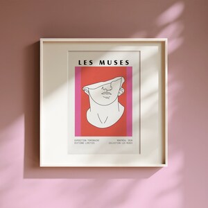 Pu&ograve; includere: Stampa artistica incorniciata con un disegno a tratto bianco di un busto classico su sfondo rosso e rosa. Il testo "LES MUSES" &egrave; in alto, con testo aggiuntivo in basso. La cornice &egrave; bianca e lo sfondo &egrave; rosa tenue.