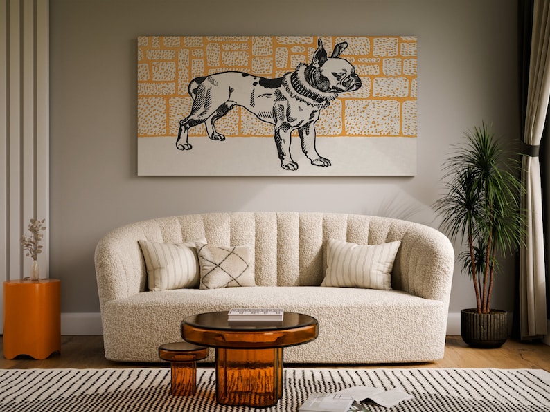 May include: A white, fluffy sofa with a black and white illustration of a dog on the wall above it. The sofa has three pillows, one with a striped pattern, one with a geometric pattern, and one with a solid color. There is a small table in front of the sofa with a glass top and a brown base.