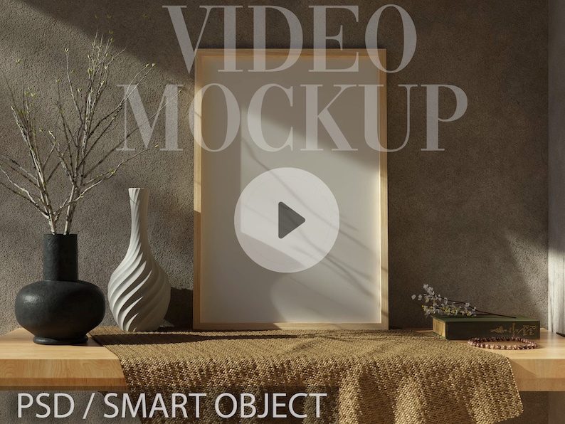 Op de afbeelding: Een houten frame met een witte achtergrond en een afspeelknop-icoon in het midden. Het frame staat op een houten tafel met een bruine doek en een vaas met een wit en zwart ontwerp. De tekst "VIDEO MOCKUP" is over de afbeelding gelegd. De tekst "PSD/SMART OBJECT" staat onderaan de afbeelding.