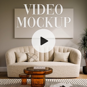 May include: A living room interior design mockup featuring a white sofa with pillows, a coffee table with a glass top, a potted plant, and a large white frame with the text "VIDEO MOCKUP" and a play button icon.