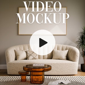 以下が含まれることがあります： リビングルームの雰囲気の中で、白いふわふわのソファにクッションが置かれています。ソファの上の壁には、大きな額縁に入った絵が飾られています。ソファの前に、コーヒーテーブルと、その横に2つの小さなテーブルが置かれています。画像の右側には、鉢植えの植物があります。額縁に入った絵の上に「VIDEO MOCKUP」という文字が表示されています。