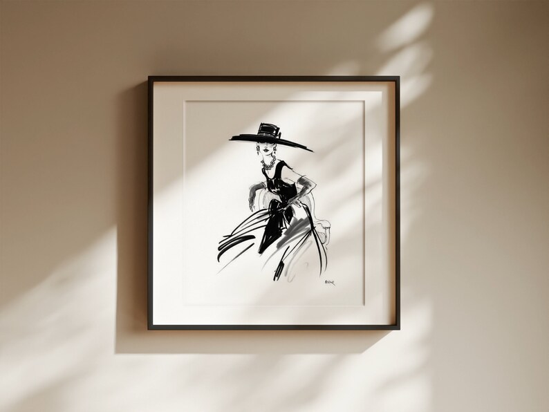 Pu&ograve; includere: Illustrazione a inchiostro nero e bianco di una persona con un cappello a tesa larga e un vestito. L'opera &egrave; incorniciata in una cornice quadrata nera e montata su una parete di colore neutro. Lo stile ricorda un bozzetto di moda.